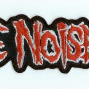 May include: Embroidered patch with the words "EXTREME NOISE TERROR" in red, stylized lettering. The text is outlined in white and set against a black background. The patch has a jagged edge.