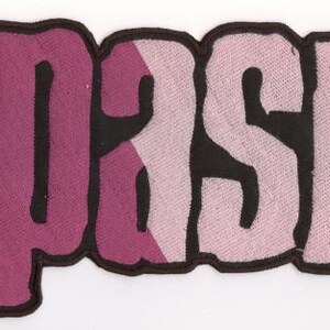 Könnte beinhalten: Ein Stoffaufnäher mit dem Wort "SPASM" in einer stilisierten Schriftart. Die Buchstaben sind hauptsächlich in einem tiefen Pink gehalten, mit einem helleren Pink-Akzent auf dem Buchstaben "A". Die Buchstaben sind schwarz umrandet.