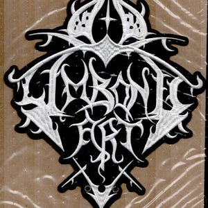 Könnte beinhalten: Schwarz-weißer gestickter Aufnäher mit dem Text "Immortal Fort". Der Aufnäher hat ein komplexes, verziertes Design mit schwarzem Hintergrund und weißen Nähten. Der Aufnäher ist rautenförmig mit dekorativen Elementen.