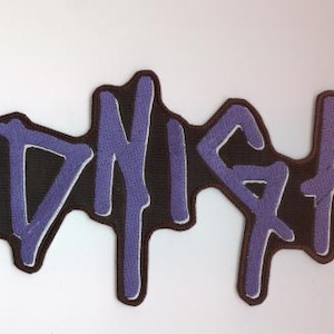Może przedstawiać: Haftowana naszywka z napisem "MIDNIGHT" w stylizowanej, ociekającej czcionce. Fioletowe litery mają białą obwódkę na czarnym tle. Odpowiednia do odzieży lub akcesoriów.
