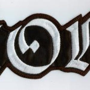 Può includere: Toppa ricamata con la scritta "STORM" in lettere gotiche bianche su sfondo nero. La toppa ha un bordo marrone. Le lettere sono spesse e stilizzate.