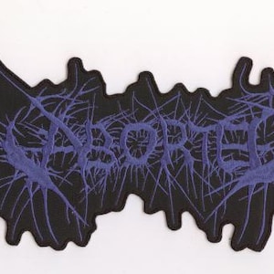 May include: A black patch with the word "ABORTED" in purple, stylized with a spidery, web-like design. The patch has an irregular shape with jagged edges.