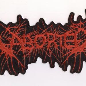 Könnte beinhalten: Schwarzer Aufnäher mit dem Wort "ABORTED" in Rot, stilisiert mit einem spinnenartigen, venenartigen Design. Der Aufnäher hat eine unregelmäßige Form, und der Text ist in einer fetten, leicht verblassten Schriftart. Für Kleidung oder Accessoires.