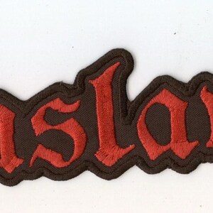 Könnte beinhalten: Ein rechteckiger gestickter Aufnäher mit dem Wort Enslaved in einer stilisierten roten gotischen Schriftart. Die Buchstaben sind mit schwarzem Garn umrandet, was einen starken Kontrast zum dunklen Hintergrund bildet. Der Aufnäher hat einen gezackten Rand.
