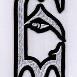May include: A black and white embroidered patch featuring a stylized letter "F". The letter has a silver-colored fill and a black border. The design has a gothic or medieval aesthetic, with sharp angles and decorative elements.