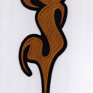 Könnte beinhalten: Ein gestickter Aufnäher in Form einer hohen, schlanken, abstrakten Flamme aus goldfarbenem Metallic-Garn. Das Design ist mit einem dicken schwarzen Rand versehen, der einen scharfen Kontrast zum goldenen Stickmuster im Inneren bildet.
