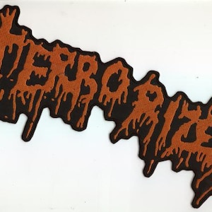 May include: A black patch with the word "TERRORIZER" in orange, dripping letters. The patch has a jagged, irregular shape and is likely designed to be sewn onto clothing or accessories. The design is bold and eye-catching.