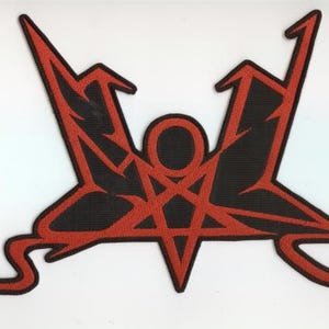 Puede incluir: Un parche bordado en negro y rojo con un diseño estilizado. El parche presenta un pentagrama central dentro de un círculo, con formas angulares que se extienden hacia afuera. El diseño está delineado en rojo sobre un fondo negro.