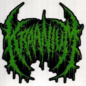 May include: A black patch with a green, stylized, dripping text design. The green text appears to be a band logo or emblem, with a jagged, organic aesthetic. The patch has a unique, irregular shape.