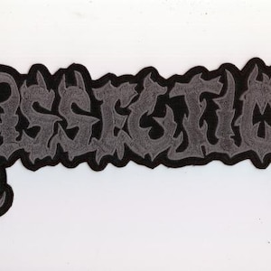 Op de afbeelding: Een zwart-grijze geborduurde patch met het woord "POSSESSED" in een gotisch lettertype. De patch heeft een zwarte rand en een witte achtergrond. De letters zijn in een gestileerd, sierlijk ontwerp.