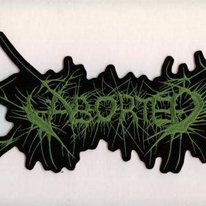 May include: Black patch with the word "ABORTED" in green, stylized text. The text is surrounded by a green, spiky design. The patch is on a white background.