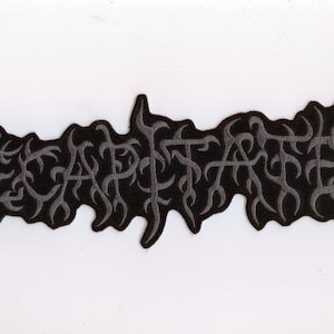 May include: Black embroidered patch with the word "DECAPITATED" in a stylized, gothic font. The patch has a dark gray border and the text is in a lighter gray color. The patch is likely for a jacket or bag.