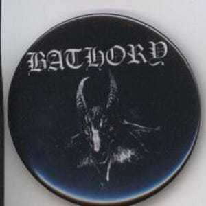 Puede incluir: Un botón redondo negro con la palabra "BATHORY" en letras góticas blancas. Debajo, una ilustración detallada de una criatura parecida a una cabra con ojos rojos. El botón tiene un acabado brillante.