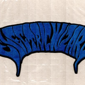 May include: A blue embroidered patch featuring the text Electric Wizard in a stylized, wavy font. The lettering is filled with a textured blue thread and outlined in a thick black border, with two pointed, downward-curving ends on each side.