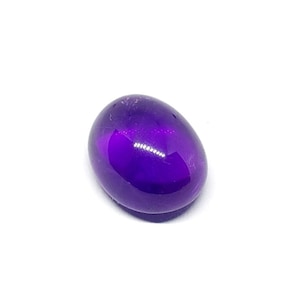 May include: A smooth, oval-shaped amethyst gemstone with a deep purple hue. The gemstone is polished and reflects light.
