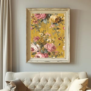 May include: A framed floral print featuring a bouquet of pink, white, and yellow roses against a mustard yellow background. The artwork is in a distressed white wooden frame, creating a vintage aesthetic. The print is hanging above a cream-colored sofa.