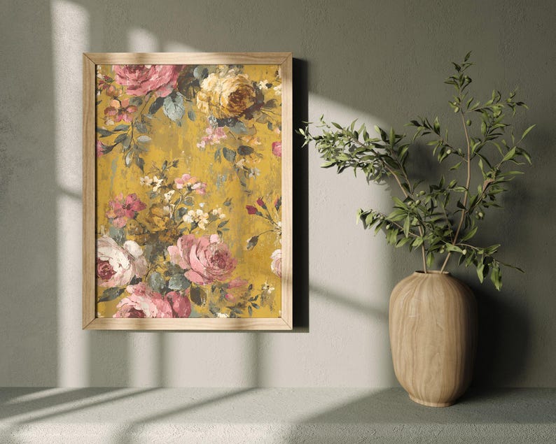 May include: A framed floral print featuring pink, yellow, and white roses on a textured yellow background. The wooden frame surrounds the artwork, which is displayed on a wall. A wooden vase with green branches is next to the framed print.