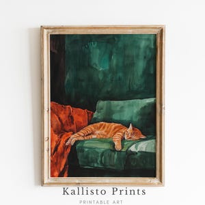 May include: A framed watercolor painting of an orange tabby cat sleeping on a green velvet couch with a red throw blanket. The background is a dark green.