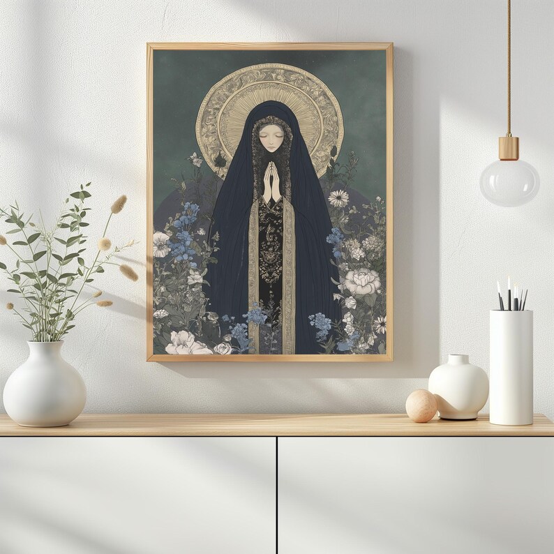 May include: A framed art print featuring a religious figure in a dark blue cloak with hands clasped in prayer. The artwork has a gold halo and is surrounded by flowers in shades of blue, white, and gray. The background is a dark teal color.