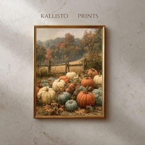 Op de afbeelding: Een ingelijste kunstdruk met de tekst KALLISTO PRINTS met een herfstlandschap. De afbeelding toont een verzameling oranje, witte en blauwgroene pompoenen die op droge bladeren liggen voor een houten hek en een bosrijke omgeving.
