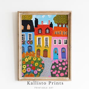 Puede incluir: Una pintura colorida de una fila de casas con paredes rojas, amarillas, azules y rosas. Las casas tienen ventanas y puertas, y hay flores delante de ellas. La pintura está enmarcada en un marco de madera claro.