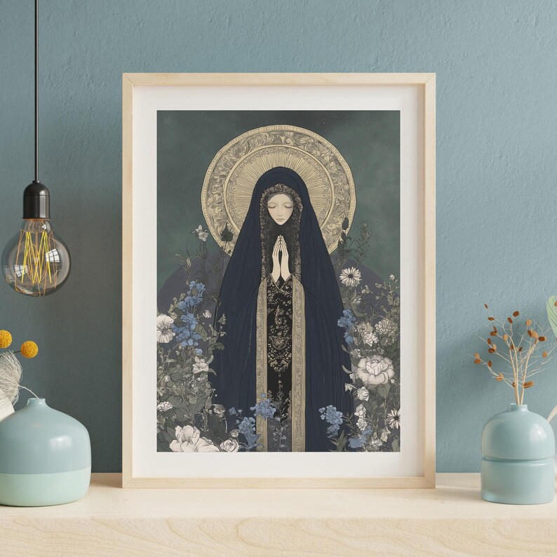 May include: Framed art print featuring a serene illustration of a figure in a dark blue veil, hands clasped in prayer. The artwork is surrounded by blue and white flowers, with a golden halo and a dark green background. The frame is light wood.