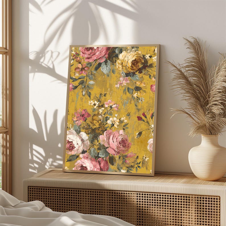 May include: A framed floral print featuring a vintage-style design. The artwork showcases a mustard yellow background with a pattern of pink, white, and yellow roses and other flowers. The frame is a light brown color.