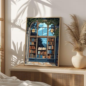 Op de afbeelding: Een ingelijste kunstdruk met het interieur van een bibliotheek met hoge boogramen, planken vol kleurrijke boeken en hangende bolvormige lampen. De scène toont een blauw raamkozijn, groen gebladerte aan de bovenkant en een bewolkte lucht.