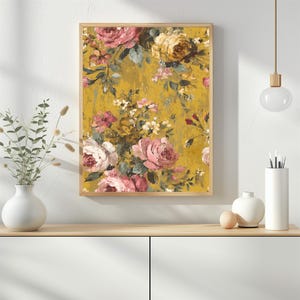 May include: A framed floral print featuring a vintage-style design. The artwork showcases a bouquet of pink and yellow roses against a textured, mustard-yellow background. The print is enclosed in a light brown wooden frame.