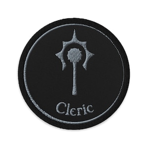 May include: Black embroidered patch with a silver-colored Cleric symbol and text. The patch is circular with a black background and a silver border. The Cleric symbol is a stylized design.