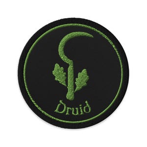 May include: Embroidered patch featuring a green design on a black circular background. The design includes a stylized sickle, oak leaves, and the word "Druid" in a script font. The patch has a green border.