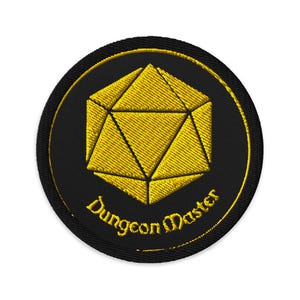May include: Round embroidered patch with a gold geometric design on a black background. The words "Dungeon Master" are arched in gold along the bottom. The patch has a gold border, ideal for fans of role-playing games.