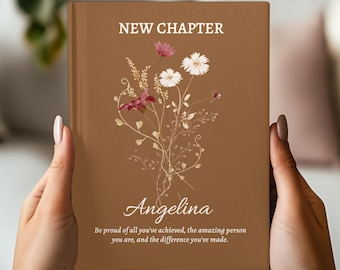 Puede incluir: Un diario marrón con las palabras "NEW CHAPTER" en la parte superior y el nombre "Angelina" debajo de un diseño floral. El diario también incluye el texto: "Siéntete orgulloso de todo lo que has logrado, de la persona increíble que eres y de la diferencia que has hecho."