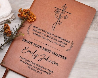 May include: A tan leather-like journal featuring a black engraved cross with floral accents. The text reads: BEHIND YOU ARE YOUR MEMORIES BEFORE YOU ARE YOUR DREAMS WITHIN YOU IS ALL YOU NEED ENJOY YOUR NEXT CHAPTER Emily Johnson Trust in the Lord with all your heart; He will make your paths straight; - Proverbs 3:5-6.
