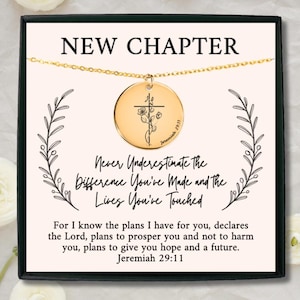 May include: A gold-colored necklace with a round pendant featuring a cross and floral design. The pendant is inscribed with "Jeremiah 29:11". The card reads "NEW CHAPTER" and a motivational quote. The necklace is presented in a black gift box.