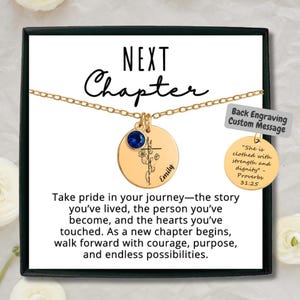 May include: A gold-colored necklace with a round pendant featuring a cross and floral design, a blue gemstone, and the name "Emily". The text "NEXT Chapter" is above the necklace. The card reads "Take pride in your journey..."