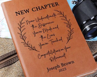 May include: A tan leather-effect journal featuring black engraved text reading NEW CHAPTER, Never Underestimate the Difference You've Made and the Lives You've Touched, Congratulations on Your Retirement, Joseph Brown, and the year 2025, framed by leaf sprigs.