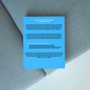 May include: A book with a light blue cover titled "DO YOU HAVE WHAT IT TAKES TO WORK WITH AI?" The book is on a grey surface. The back cover contains text about artificial intelligence and passive income.