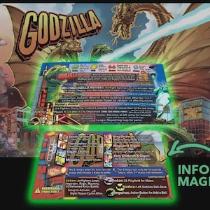 May include: A rectangular Godzilla pinball machine instruction magnet featuring two distinct sections with detailed game rules, mission objectives, and character graphics including King Ghidorah, Mechagodzilla, and Mothra, set against a vibrant city scene.