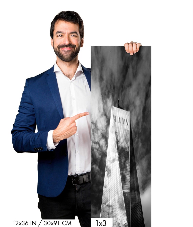 Puede incluir: Fotograf&iacute;a en blanco y negro de un rascacielos contra un cielo nublado. La imagen mide 30x91 cm. Una persona con una blazer azul y camisa blanca sostiene la fotograf&iacute;a y la se&ntilde;ala.