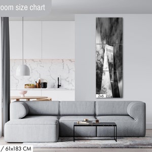 Puede incluir: Un sal&oacute;n moderno con un sof&aacute; seccional gris, una mesa de centro negra y una gran obra de arte en blanco y negro de un rascacielos. La obra de arte mide 61x183 cm. El texto "Livingroom size chart" est&aacute; en la parte superior.