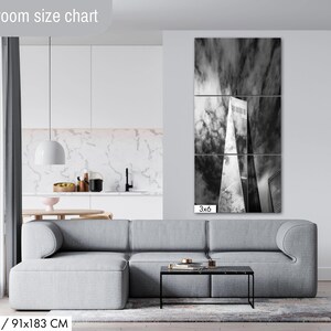 Puede incluir: Impresi&oacute;n en lienzo de tres paneles que representa una fotograf&iacute;a en blanco y negro de un rascacielos contra un cielo nublado. La obra de arte se exhibe sobre un sof&aacute; gris en un sal&oacute;n moderno. Dimensiones: 91x183 cm.