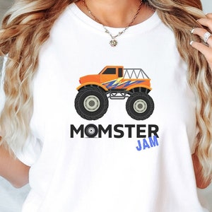 May include: White t-shirt with an orange monster truck graphic and the text "MOMSTER JAM" in blue and black lettering.