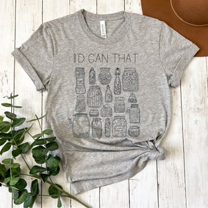 May include: A gray t-shirt with the text "I'd Can That" printed on the front. The shirt features a design of various jars filled with different items.