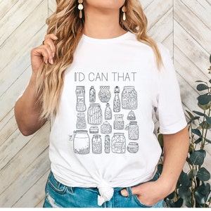 May include: White t-shirt with a black and white illustration of jars and the text "I'd Can That".