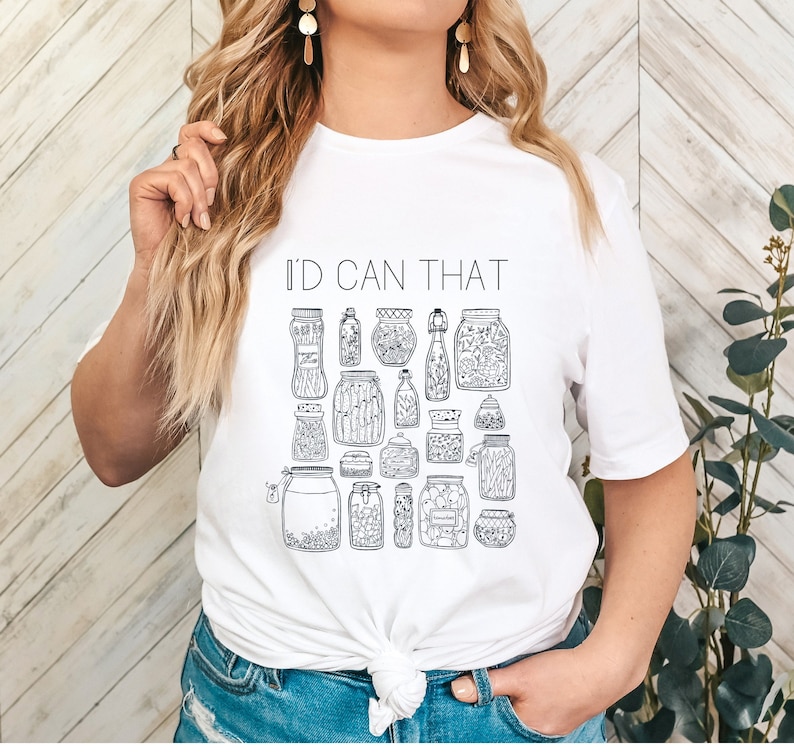 May include: White t-shirt with a black and white illustration of jars and the text "I'd Can That".