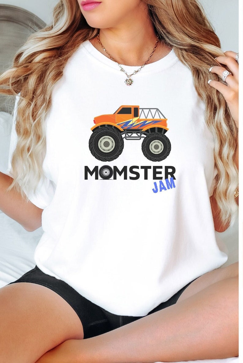 May include: White t-shirt with an orange monster truck graphic and the text "MOMSTER JAM" in blue and black lettering.
