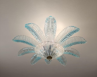 May include: A light blue glass ceiling fixture with a palm leaf design. The fixture has a central dome and eight leaves that extend outward.