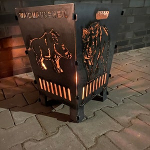 Op de afbeelding: Een zwarte metalen vuurkorf met uitgesneden dierenontwerpen en het woord "WAIDMANNSHEIL" bovenaan. De vuurkorf heeft een vierkante basis en een taps toelopende bovenkant, met verticale sleuven voor ventilatie. De dierenontwerpen omvatten een wild zwijn en een bizon.