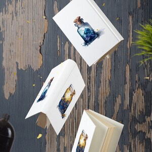 Puede incluir: Tres libros blancos con ilustraciones de acuarela de frascos llenos de purpurina azul y dorada. Los libros flotan en el aire sobre un fondo de madera azul y marr&oacute;n. Hay un tel&eacute;fono rotatorio verde vintage y un reloj despertador negro en el fondo.